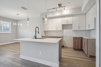 an open kitchen with a large white island and white cabinets at The Falls of Portofino Apartment, Naples, FL, 34119